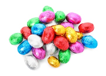 Photo of Many chocolate eggs wrapped in bright foil on white background, top view