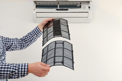 Photo of Man cleaning air conditioner filters indoors, closeup