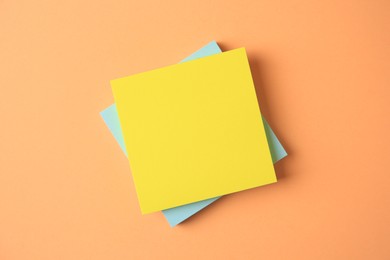 Blank paper notes on pale orange background, flat lay