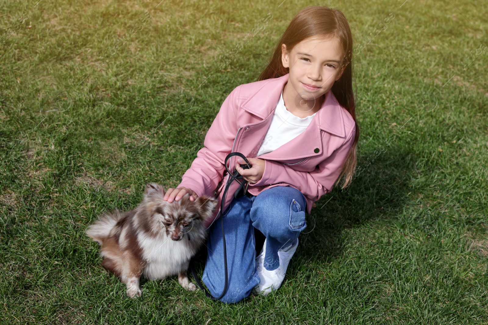 Photo of Little girl with her cute dog walking on green grass
