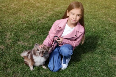 Photo of Little girl with her cute dog walking on green grass