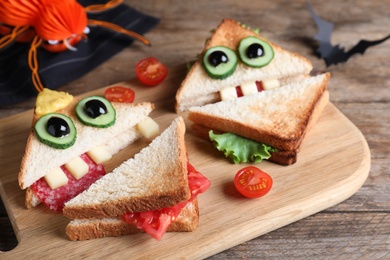 Cute monster sandwiches served on wooden board, closeup. Halloween party food