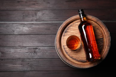 Photo of Barrel, bottle and glass of tasty whiskey on wooden table, top view. Space for text