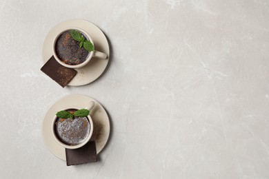 Photo of Cupsdelicious hot chocolate with fresh mint on grey table, flat lay. Space for text