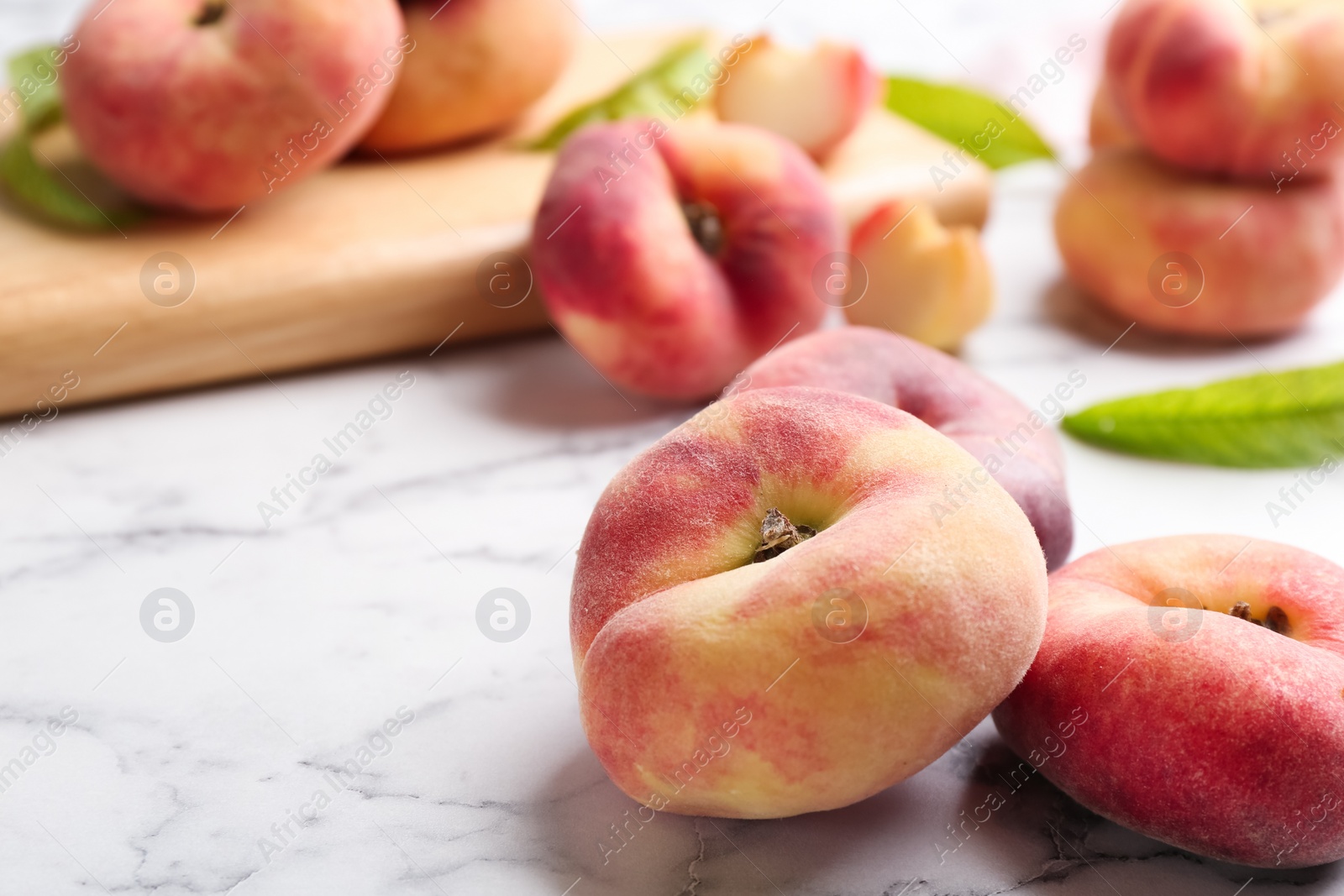 Photo of Fresh ripe donut peaches on white marble table, closeup