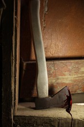 Photo of Axe with blood on wooden threshold indoors