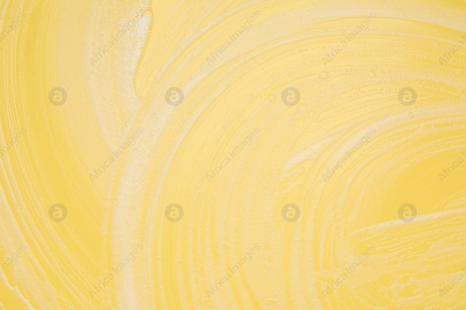 Photo of White washing foam on yellow background, top view