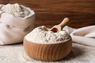 Photo of Wooden bowl with quinoa flour and scoop on table