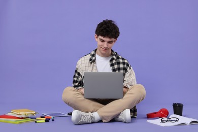 Photo of Portrait of student with laptop and stationery sitting on purple background