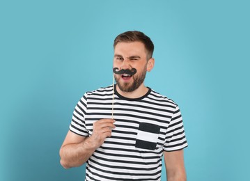Funny man with fake mustache on turquoise background