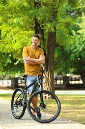 Handsome man with modern bicycle in park