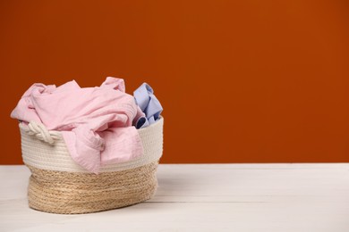 Photo of Laundry basket with clothes near brown wall. Space for text