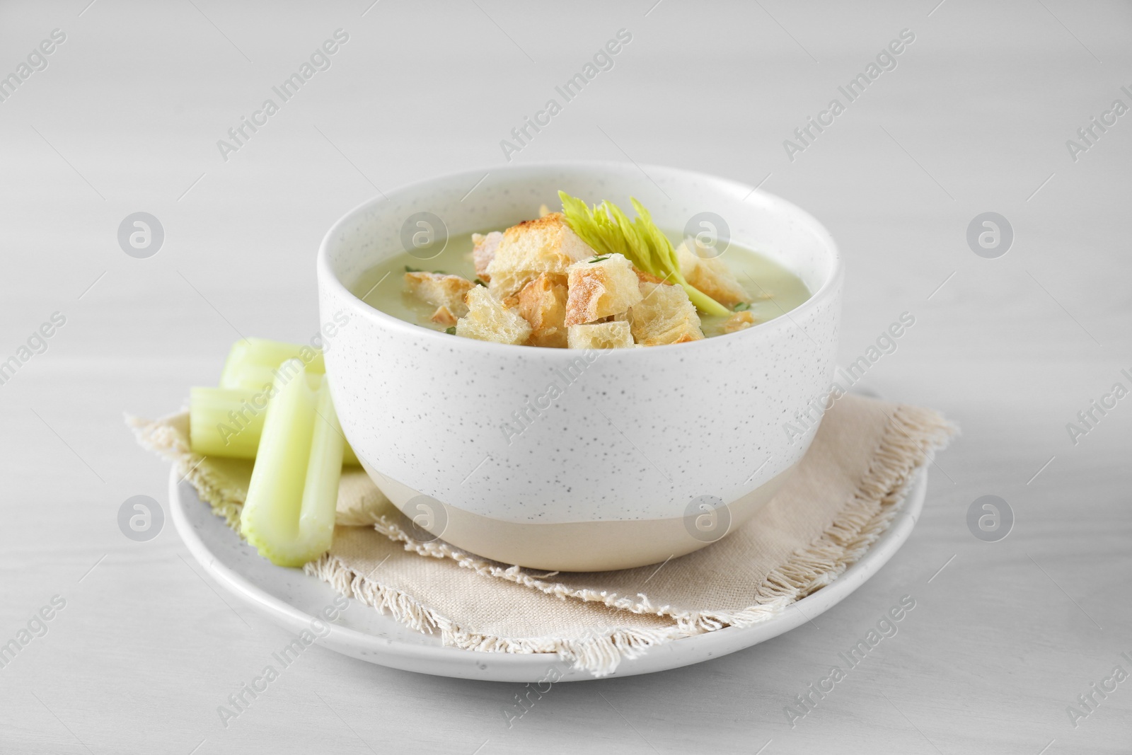 Photo of Bowl of delicious celery soup on white table, closeup