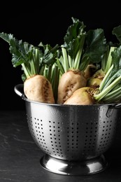 Photo of Colander with fresh sugar beets on black table