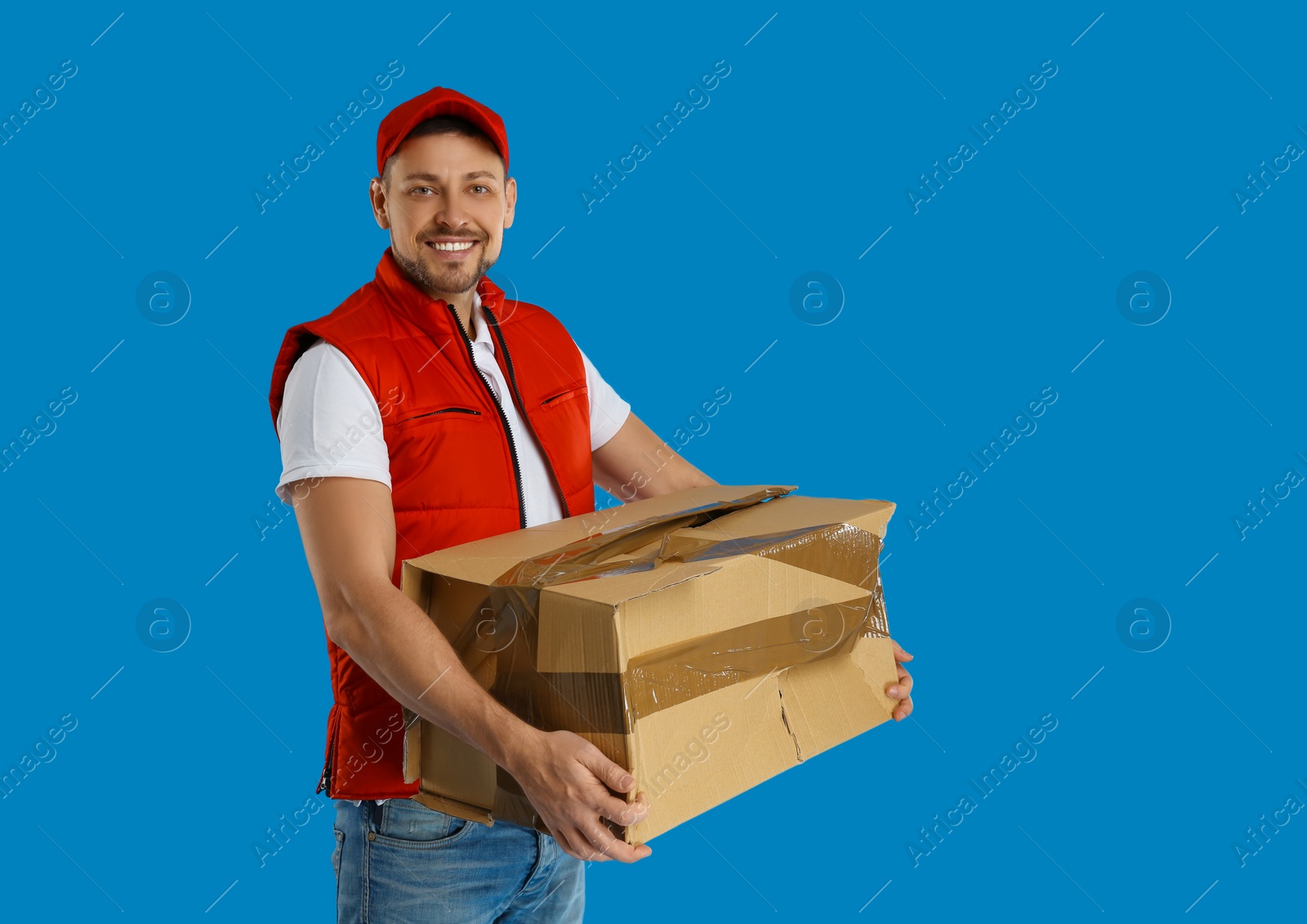 Photo of Courier with damaged cardboard box on blue background. Poor quality delivery service