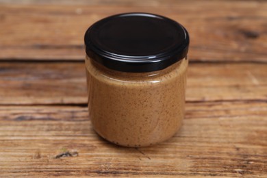 Tasty nut paste in jar on wooden table, closeup