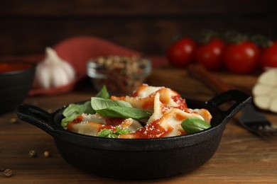 Photo of Tasty ravioli with tomato sauce served on wooden table