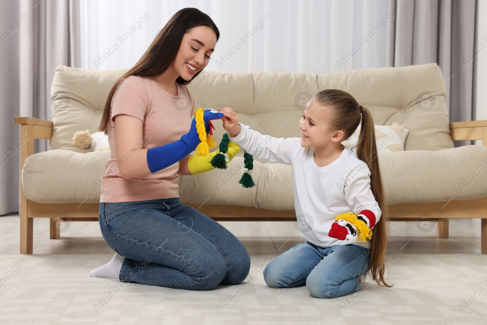 Photo of Happy mother and daughter playing with funny sock puppets together at home