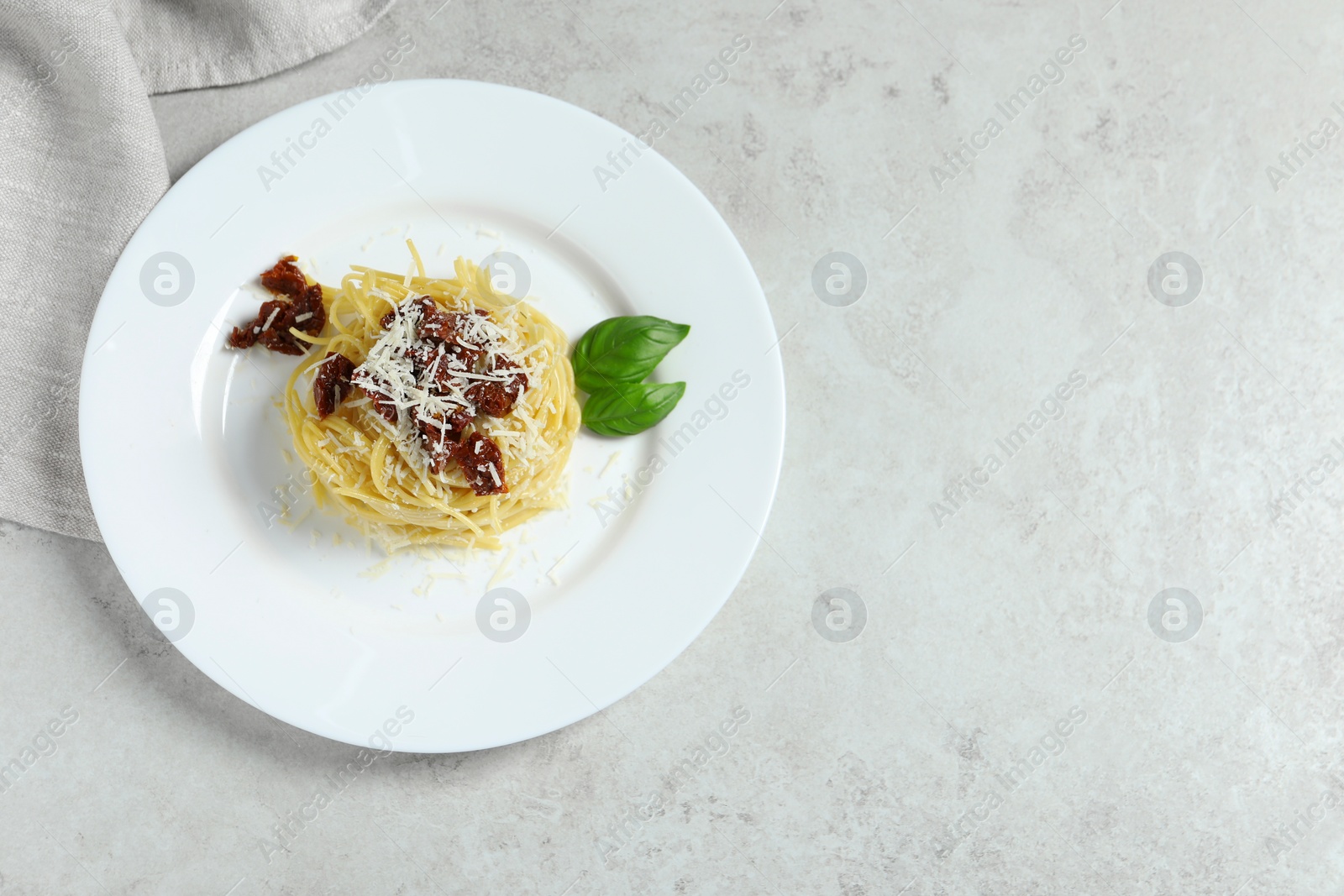 Photo of Tasty spaghetti with sun-dried tomatoes and parmesan cheese on white table, top view and space for text. Exquisite presentation of pasta dish