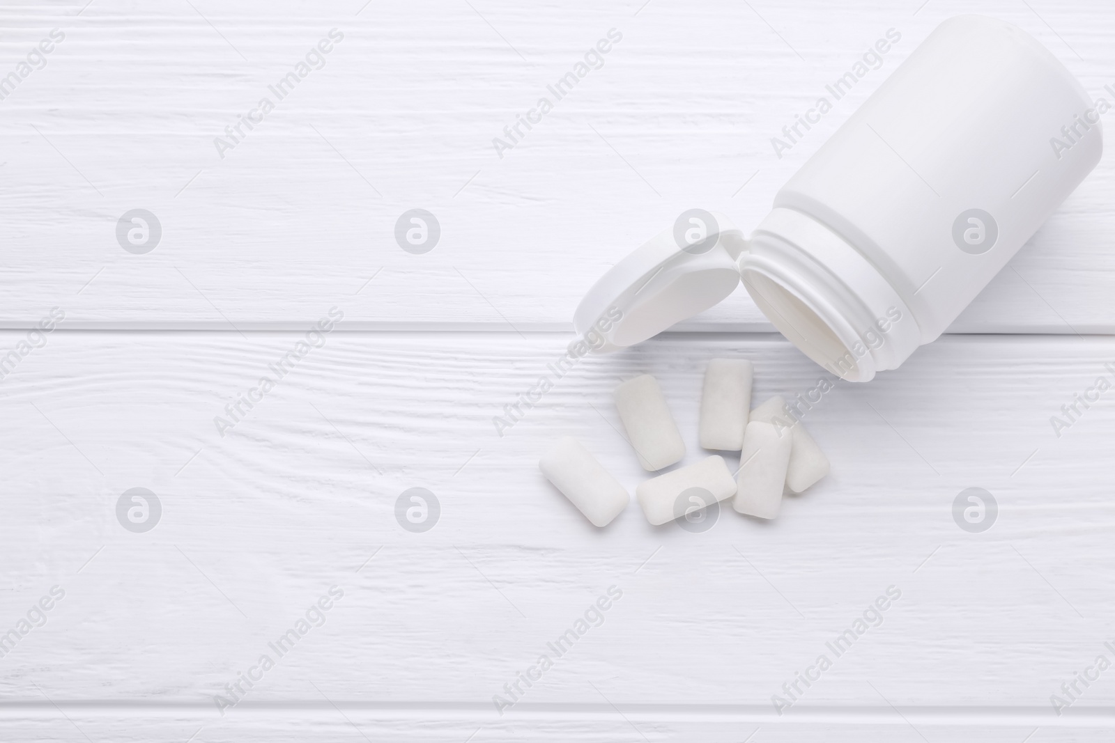 Photo of Jar with chewing gums on white wooden table, flat lay. Space for text