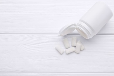 Jar with chewing gums on white wooden table, flat lay. Space for text