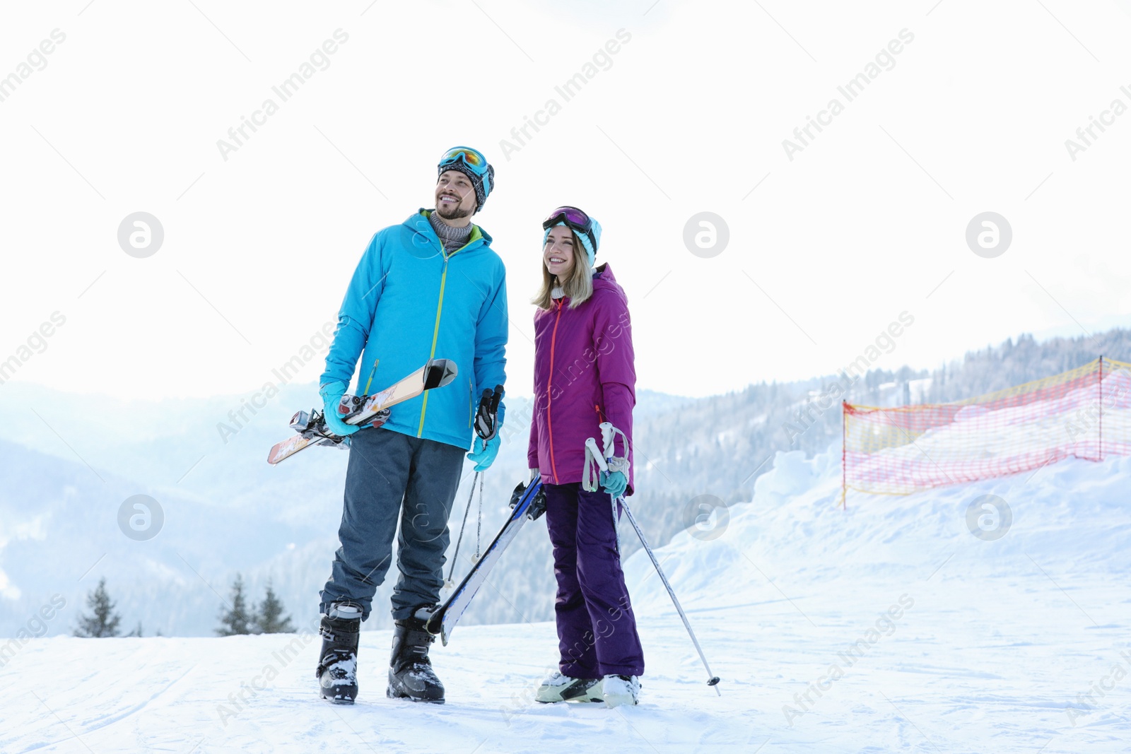 Photo of Happy couple with ski equipment spending winter vacation in mountains. Space for text