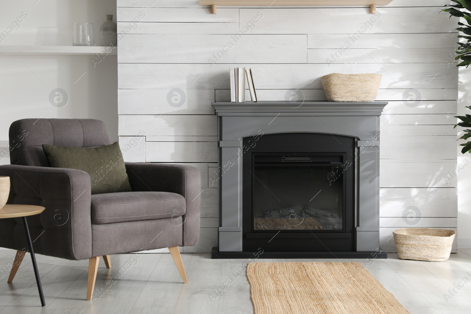 Photo of Cozy living room interior with comfortable armchair and modern electric fireplace