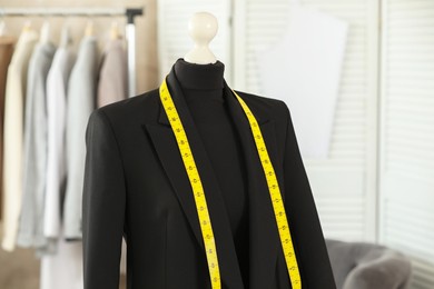 Photo of Mannequin with black jacket and measuring tape in tailor shop
