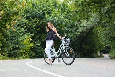 Photo of Beautiful woman in casual outfit with bicycle outdoors