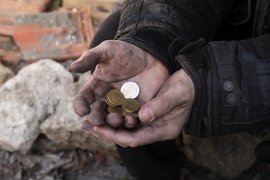 Poor homeless man holding coins outdoors, closeup