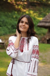Photo of Beautiful woman wearing embroidered shirt in village. Ukrainian national clothes