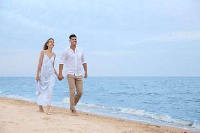 Happy couple having romantic walk on beach. Space for text