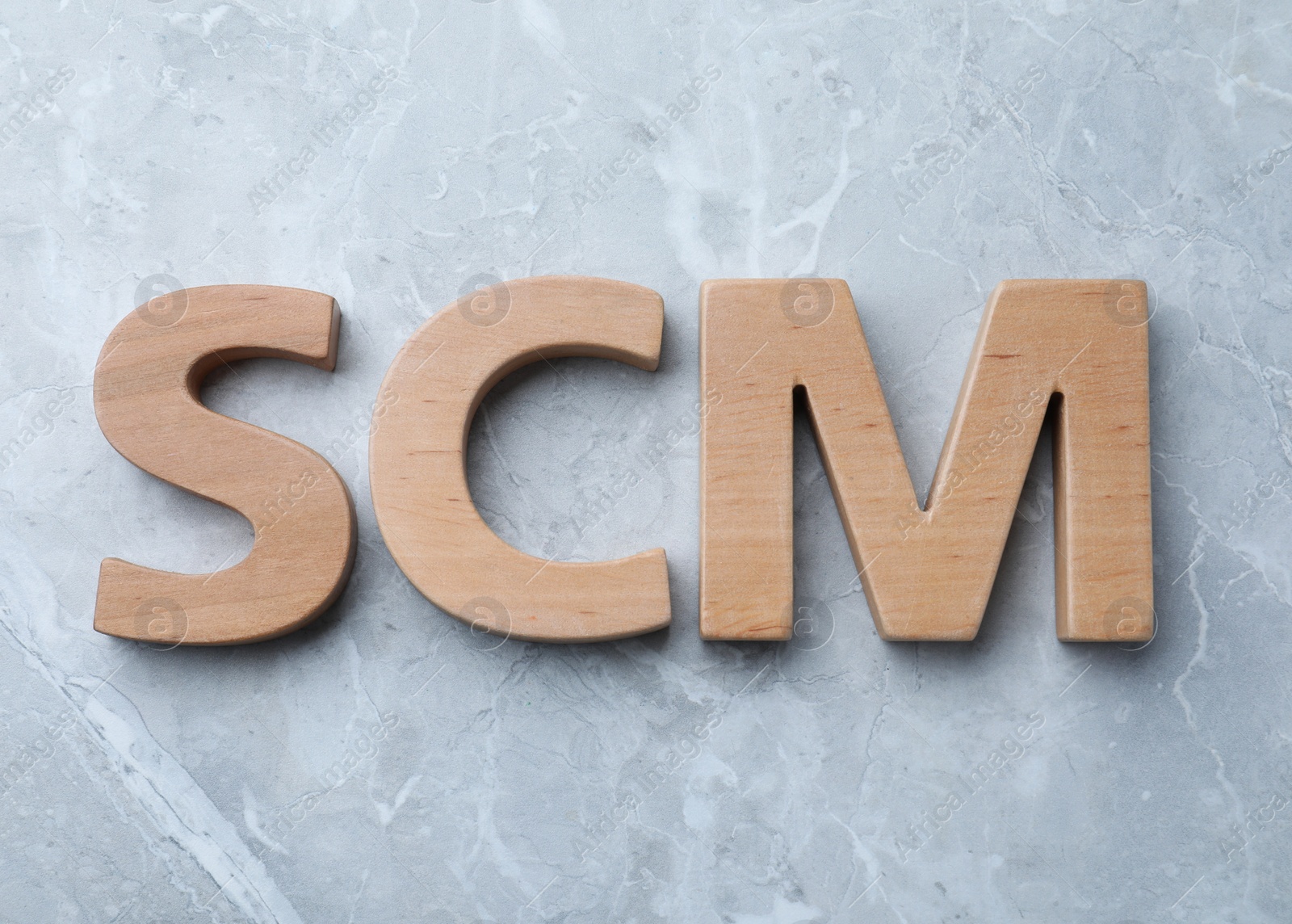 Photo of Abbreviation SCM (Supply Chain Management) made of wooden letters on light grey marble background, flat lay