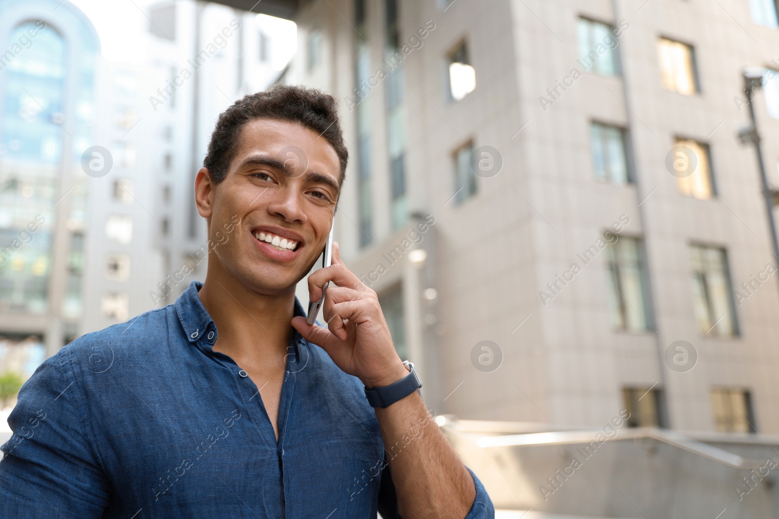 Photo of Portrait of handsome young African-American man talking on mobile phone outdoors. Space for text