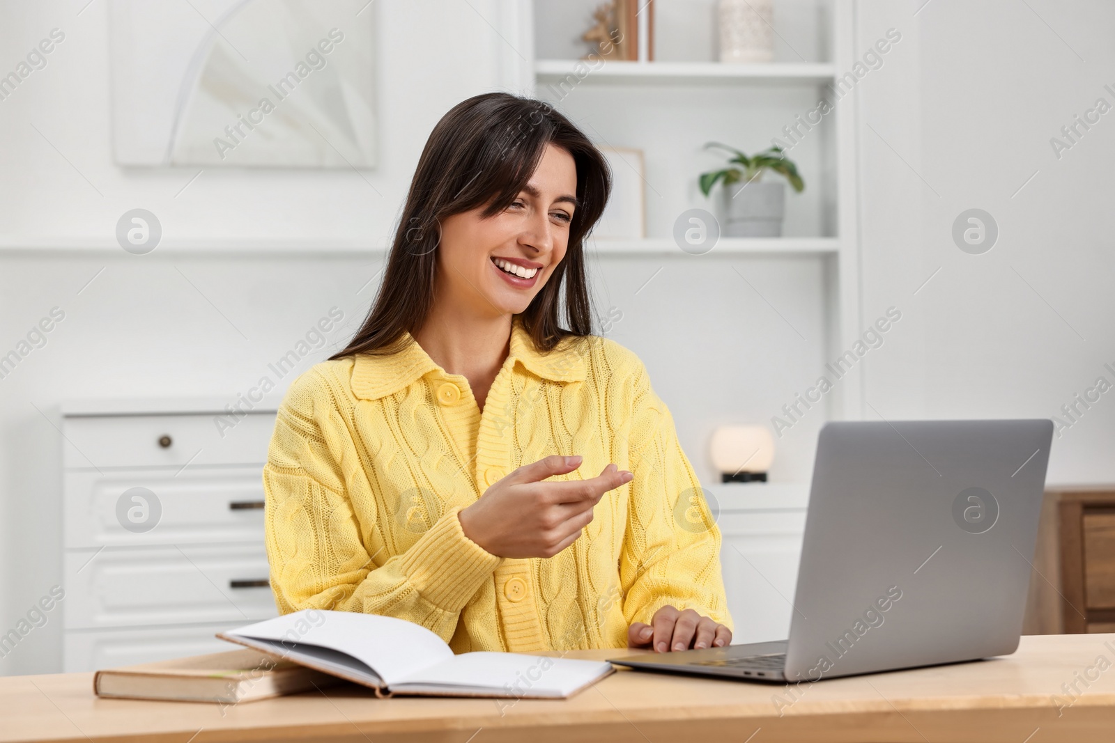 Photo of Happy woman having video chat via laptop at table indoors