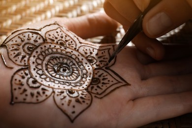 Master making henna tattoo on hand, closeup. Traditional mehndi