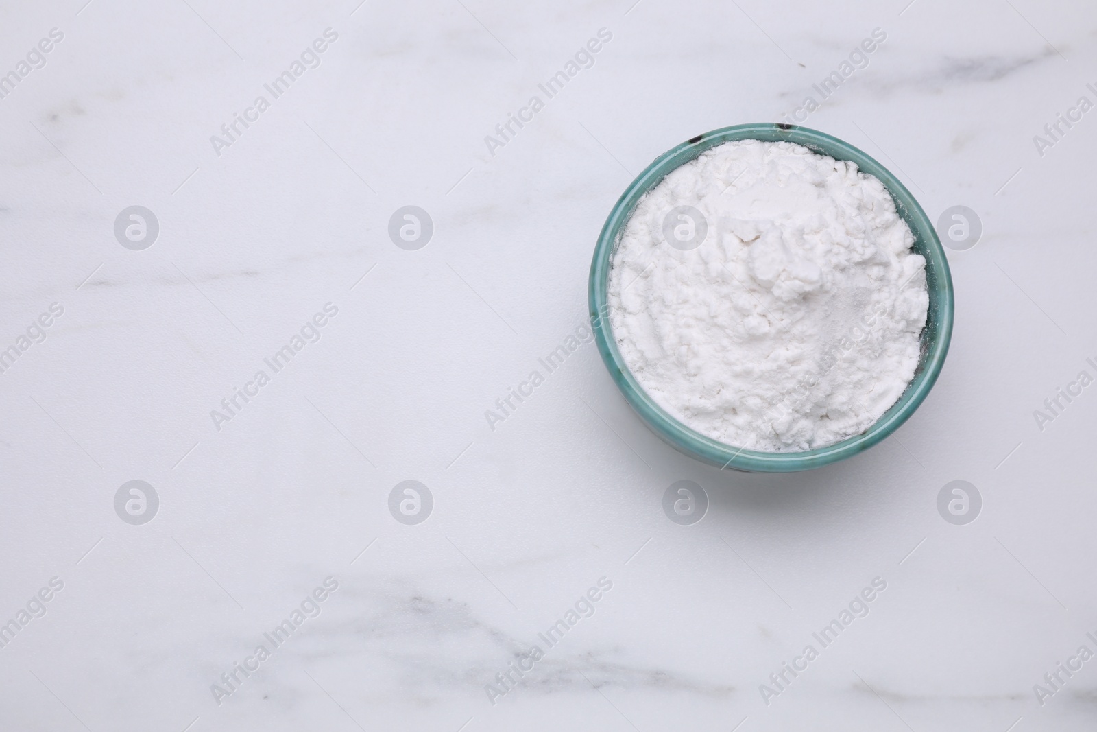 Photo of Bowl of natural starch on white marble table, top view. Space for text