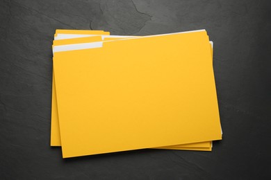 Yellow files with documents on black slate table, top view