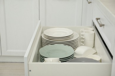 Clean plates, cups and butter dish in drawer indoors