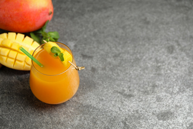 Photo of Fresh delicious mango drink on grey table. Space for text