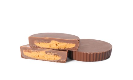 Photo of Cut and whole delicious peanut butter cups on white background