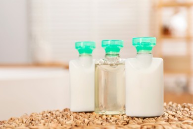 Mini bottles of cosmetic products on wicker mat against blurred background. Space for text