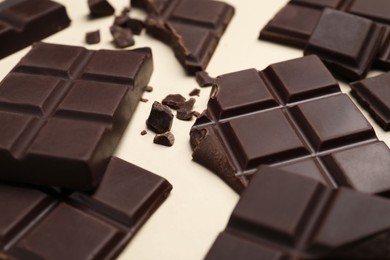 Photo of Pieces of delicious chocolate bars on beige background, closeup