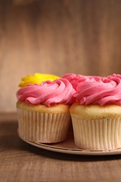 Photo of Delicious cupcakes with bright cream on wooden table, closeup