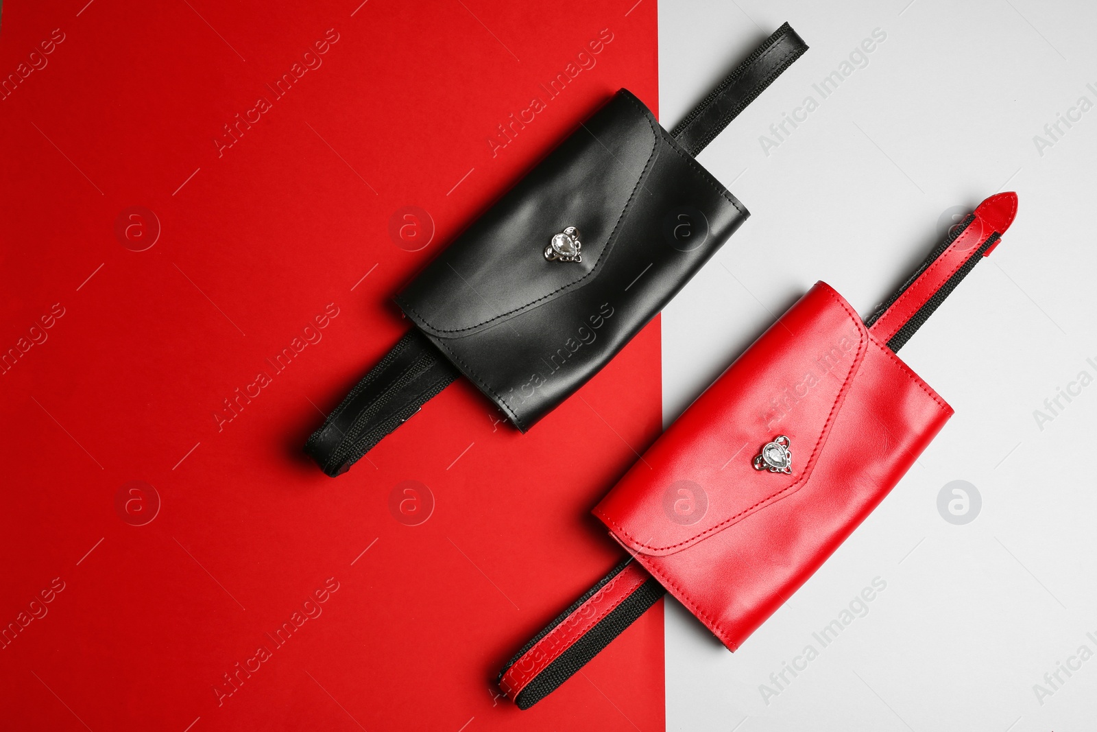 Photo of Flat lay composition of stylish bum bags on color background