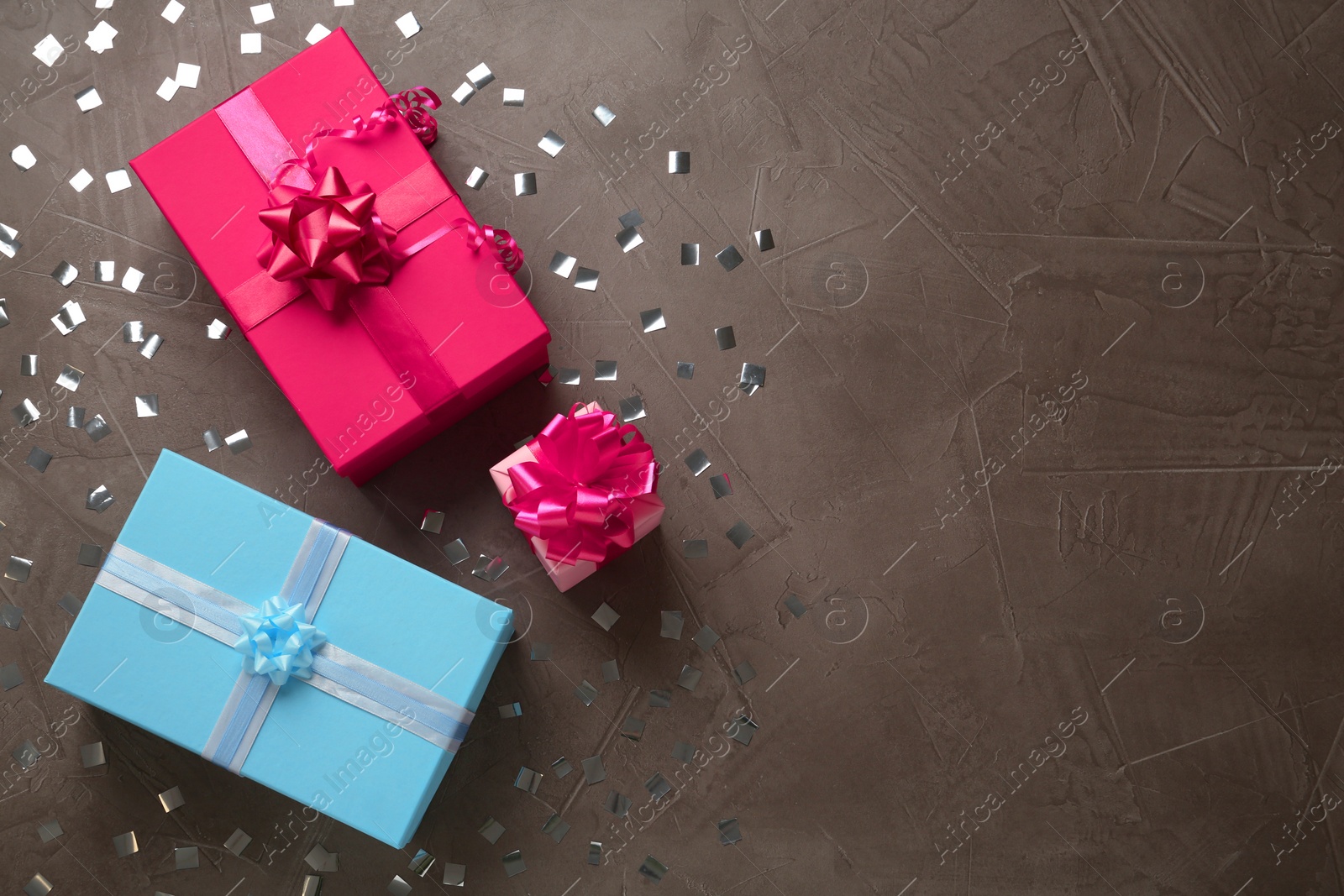 Photo of Gift boxes and shiny confetti on brown textured background, flat lay. Space for text