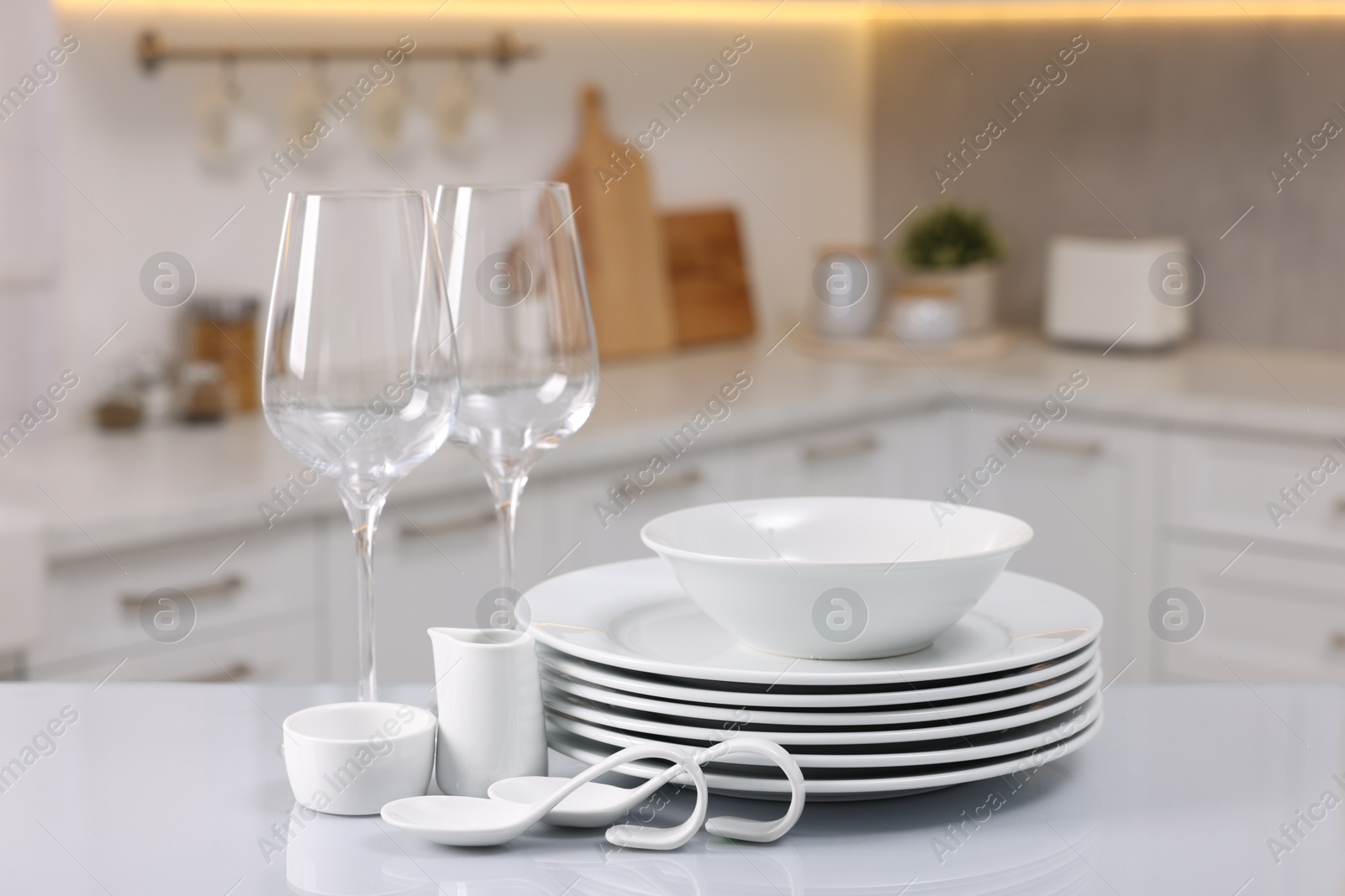 Photo of Set of clean dishware and glasses on table in kitchen