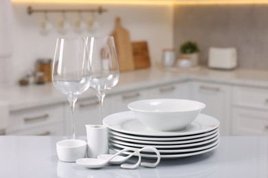 Set of clean dishware and glasses on table in kitchen