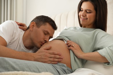 Photo of Young pregnant woman with her husband in bedroom