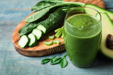 Delicious green juice and fresh ingredients on light blue wooden table, closeup. Space for text